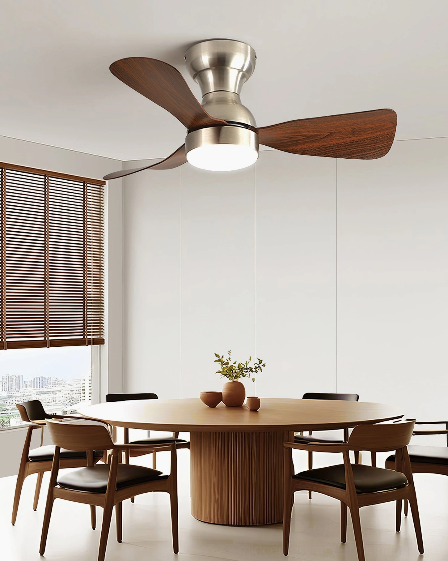 Modern dining room with round wooden table below ceiling fan light featuring dark wood blades, integrated LED, and warm neutral contemporary décor