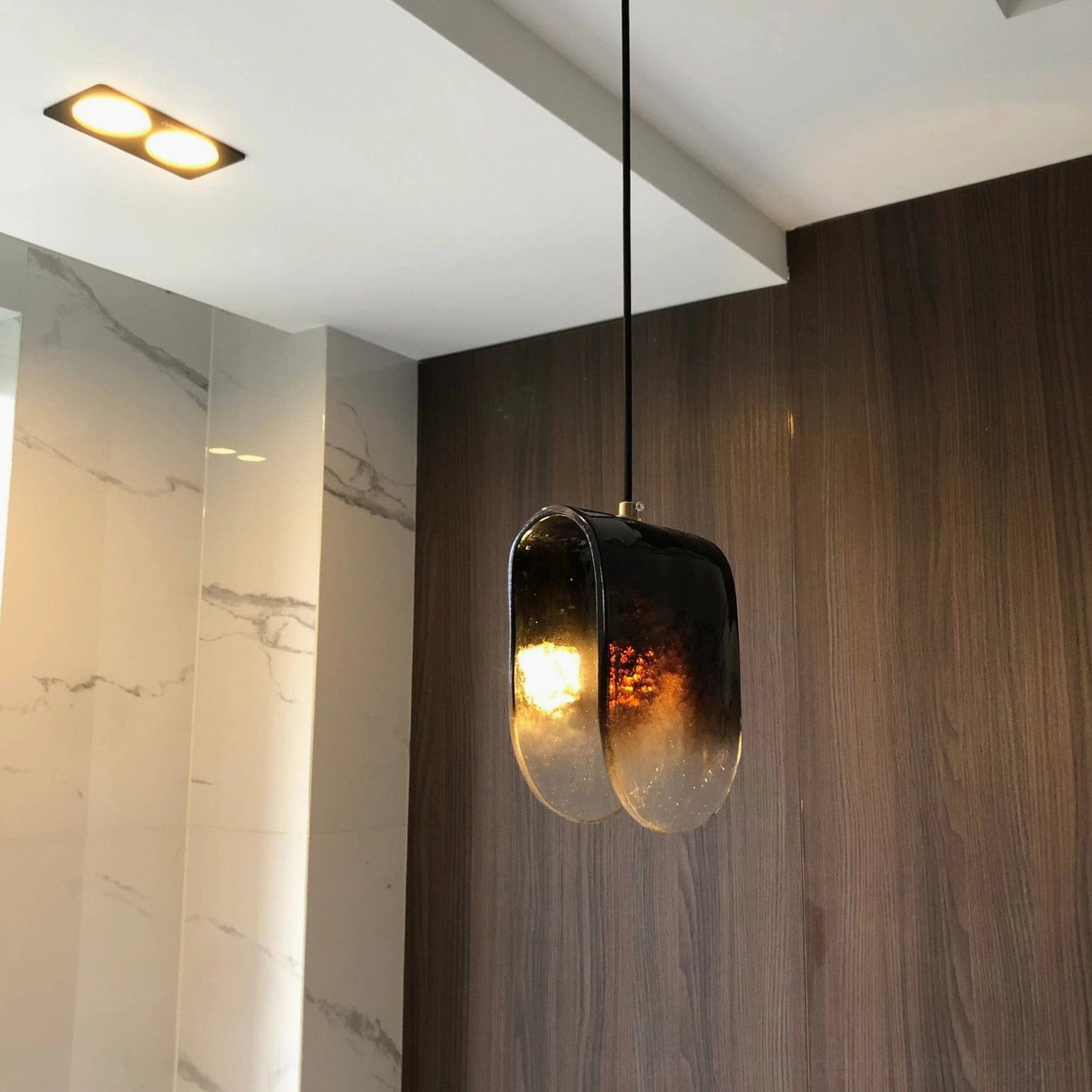 Contemporary hand-blown glass pendant showing artistic purple-to-clear color transition