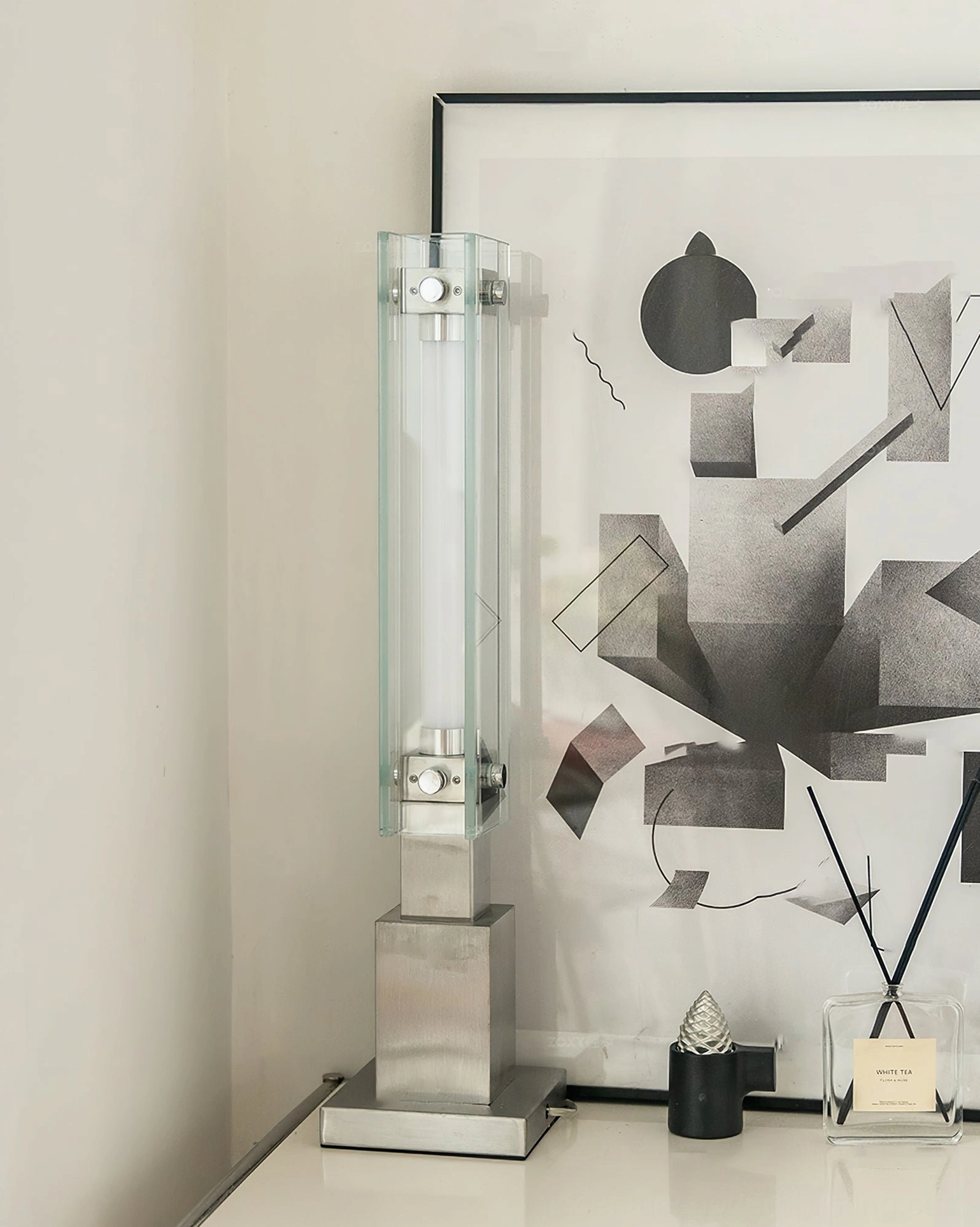 Three-quarter front angle of glass table lamp on vanity with geometric abstract wall art