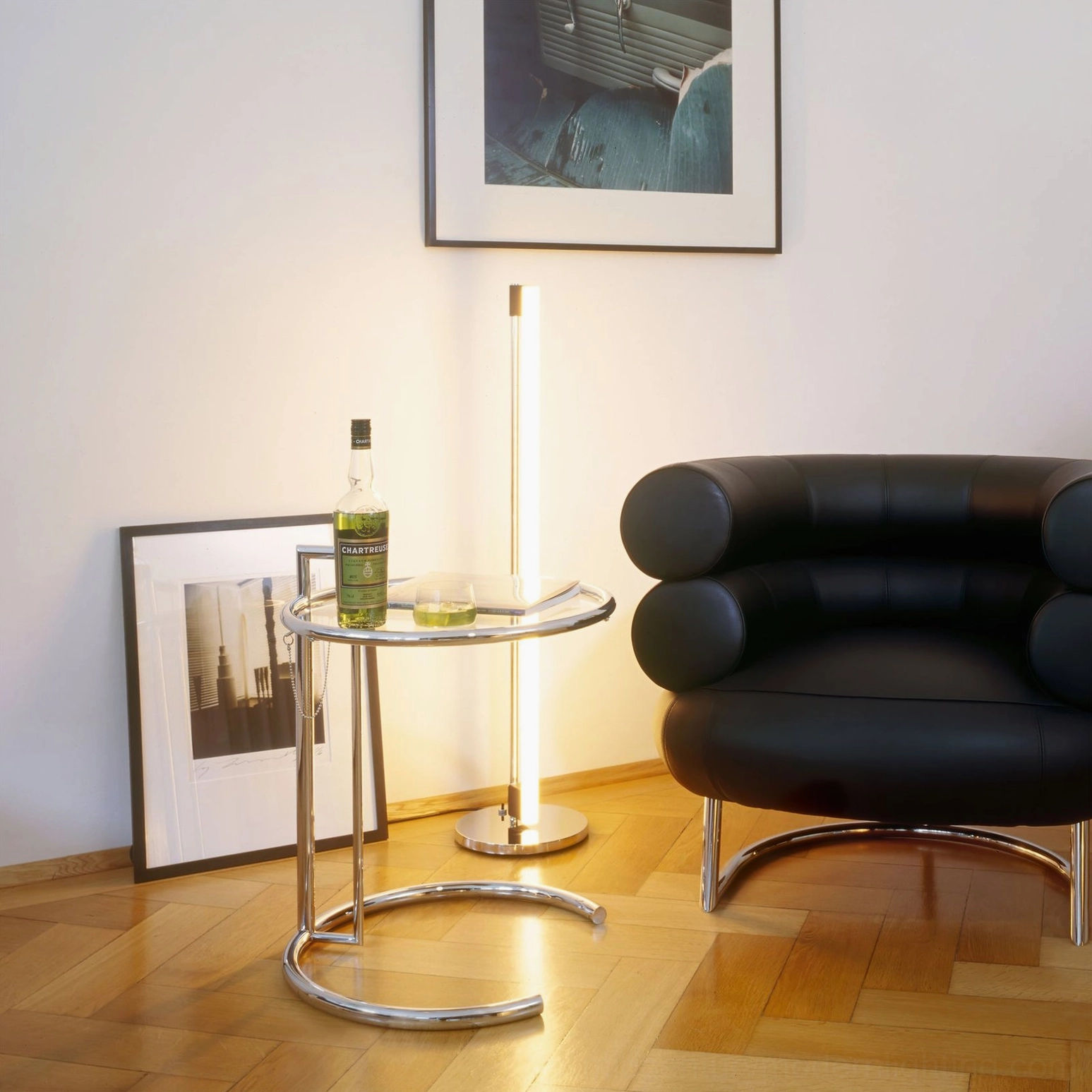 Tube LED floor lamp side view next to black leather armchair showing warm ambient glow in living room