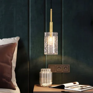 Coralie brass pendant light installed above dark green velvet bedroom wall with coordinating glass decor accessories