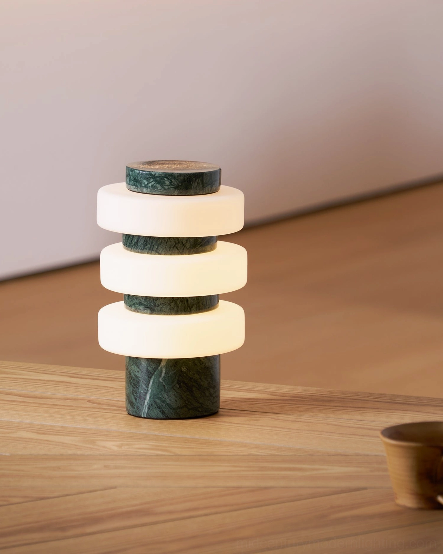 Close-up of Corba compact table lamp with green marble base and frosted stacked glass rings, minimalist design