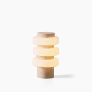Corba sculptural table lamp with beige travertine base and stacked frosted glass rings on white studio background