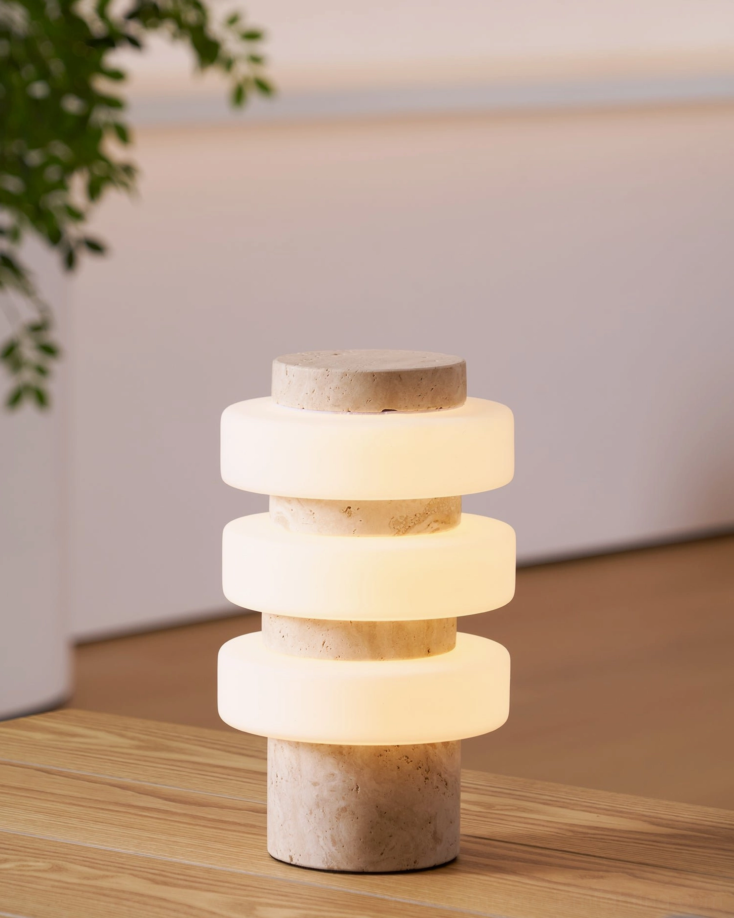 Corba layered glass table lamp with travertine stone base and houseplant on rustic wooden table