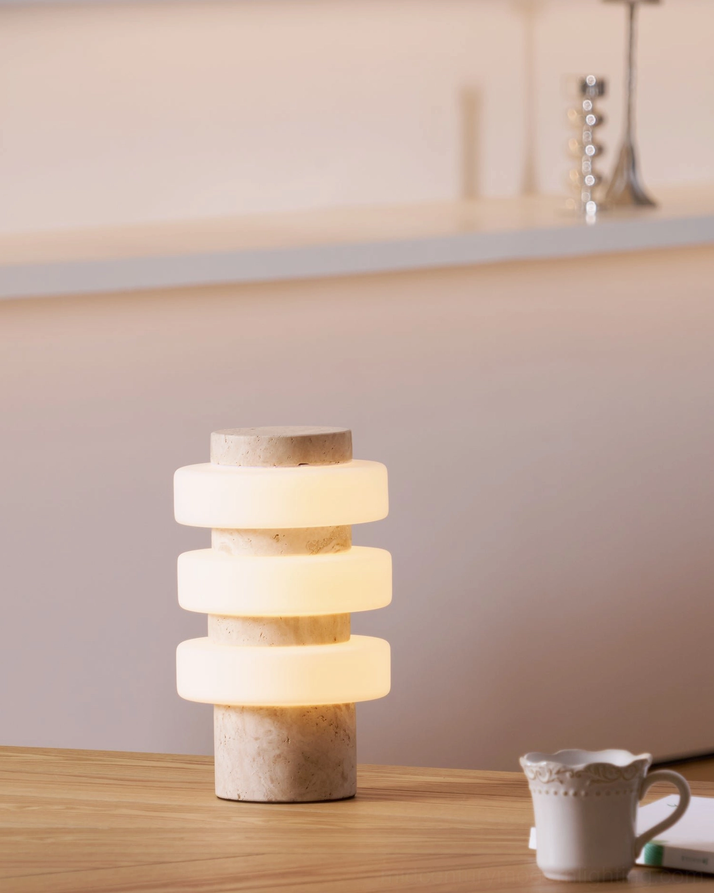 Corba stacked glass table lamp with beige travertine base in minimalist wooden table interior setting