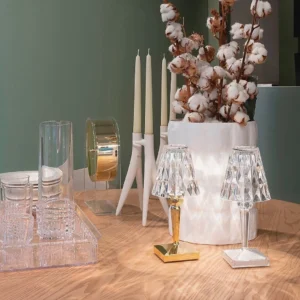 Two crystal LED table lamps with gold and white metal bases on wooden table, ambient lighting comparison