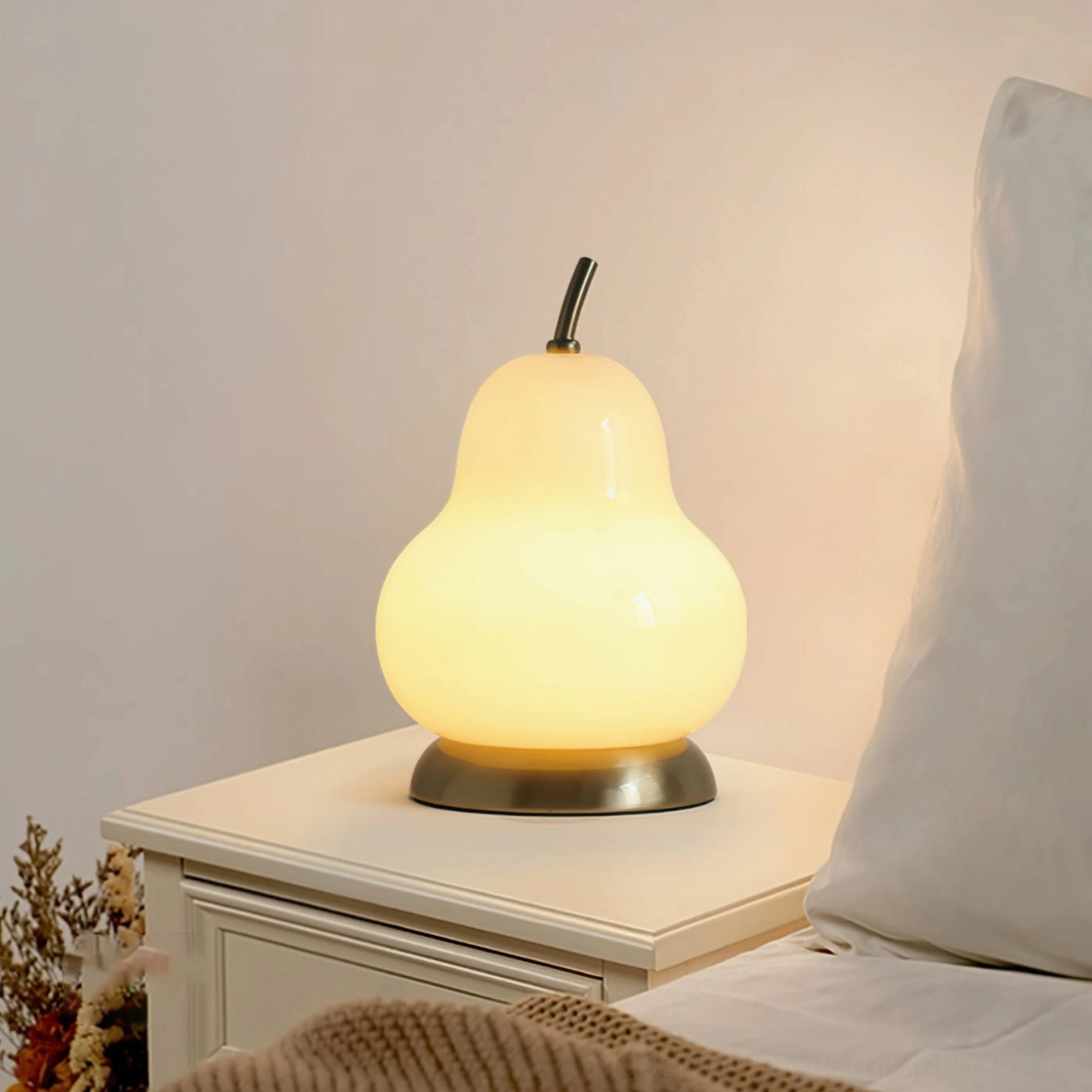 Illuminated pear glass cordless lamp on bedroom nightstand, creating warm ambient glow in contemporary bedroom setting
