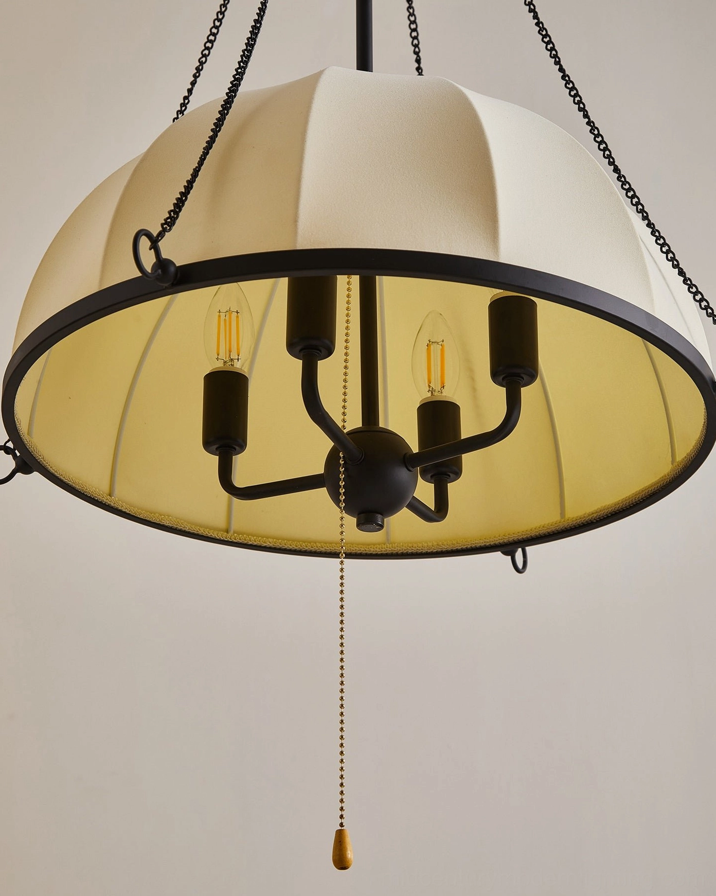 Close-up of Covina pendant lamp showing candle bulb bases, ribbed fabric shade, and black metal trim