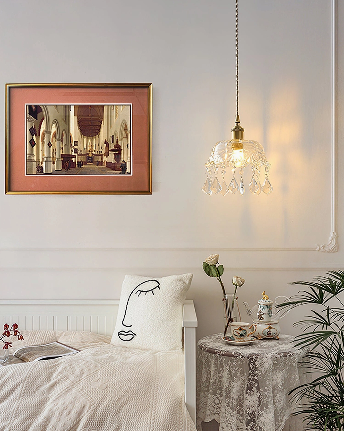 Cozy bedroom with crystal jewel pendant light, framed artwork, vintage lace side table
