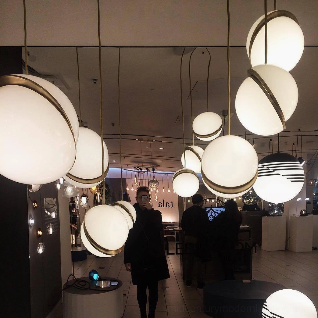 Architectural crescent pendant light with sculptural opal sphere and metal fascia