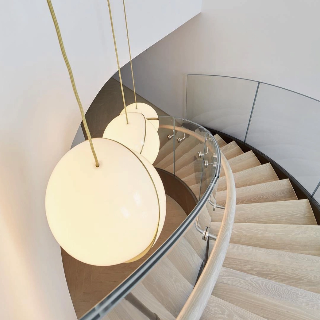 Multi-head crescent pendant lights suspended over modern spiral staircase with warm ambient glow