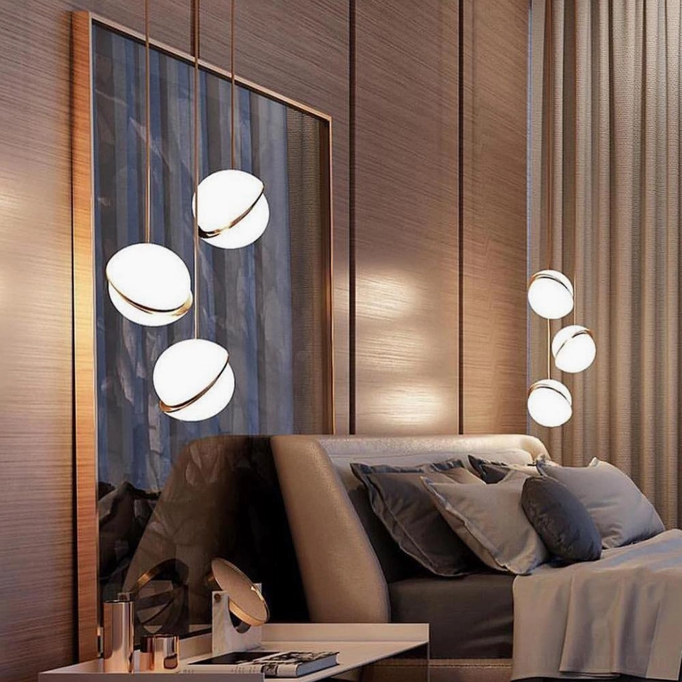 Multiple crescent pendant lights paired with wall sconces in modern luxury bedroom with wood panels