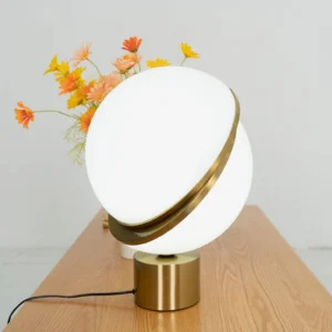 Mid-century modern Crescent Sphere Table Light lit on wooden console with fresh flowers creating warm ambient glow