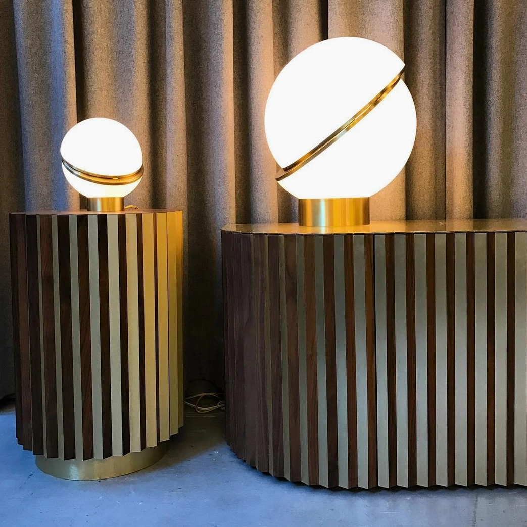 Pair of Crescent Sphere Table Lights displayed on upscale fluted stands with grey curtains in background