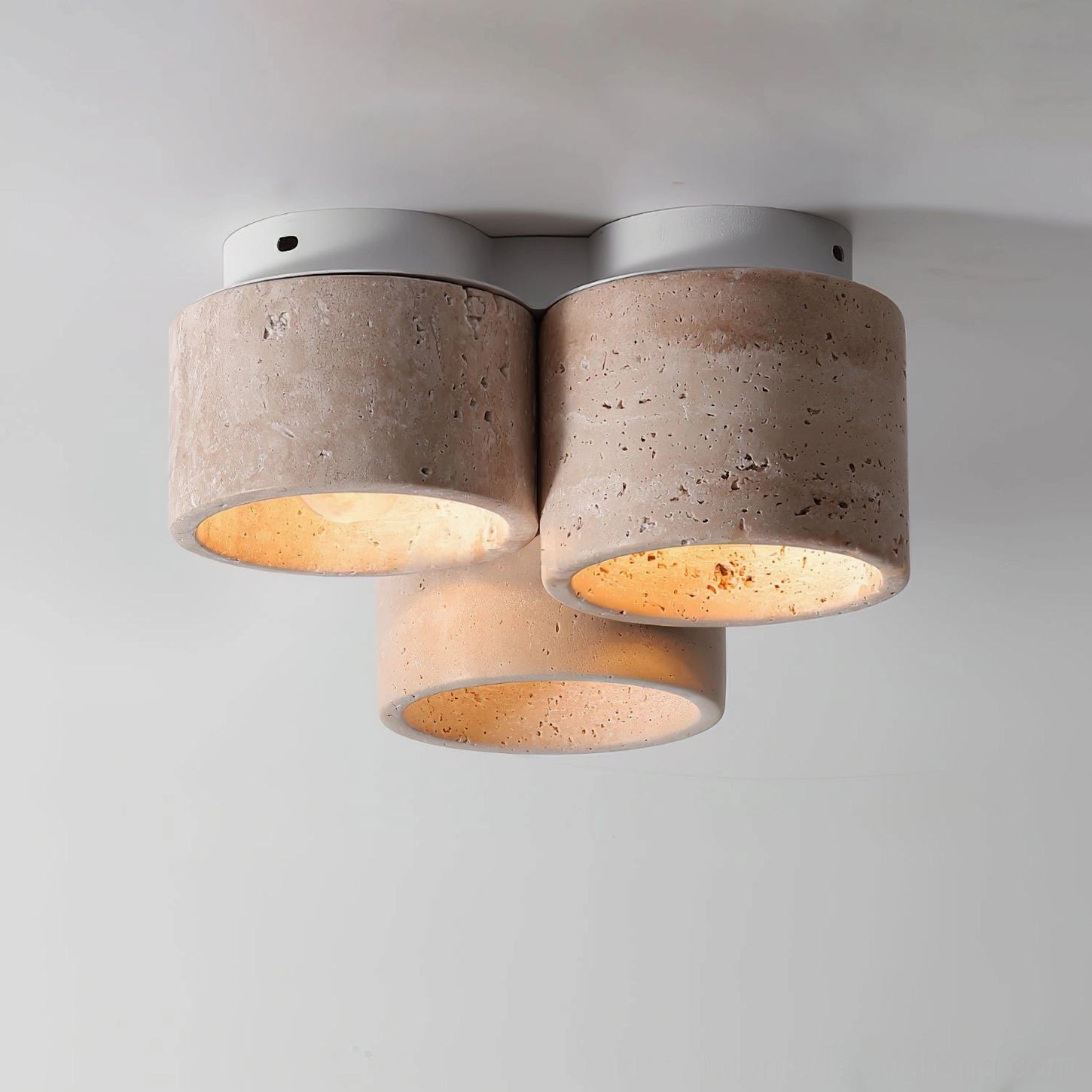 Close-up detailed view of Cromia travertine ceiling light highlighting rough natural stone texture with warm internal illumination