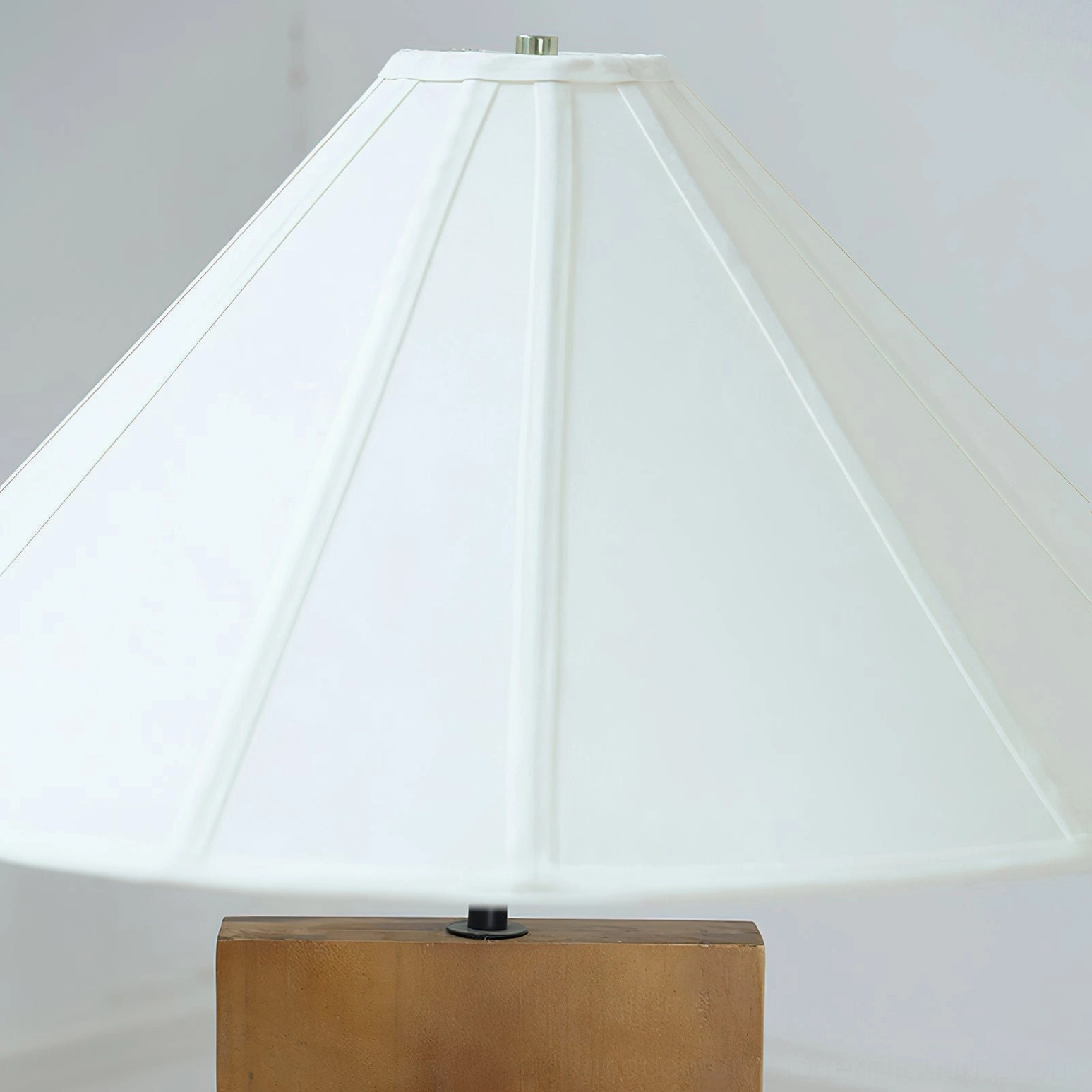 Close-up detail of crossbase lamp white pleated fabric shade and matte black metal hardware