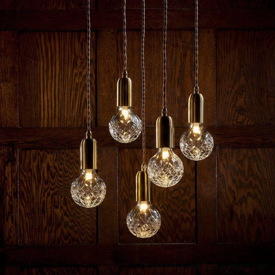 Close-up detail of crystal bulb pendant showing faceted glass and brass fixture with warm LED glow