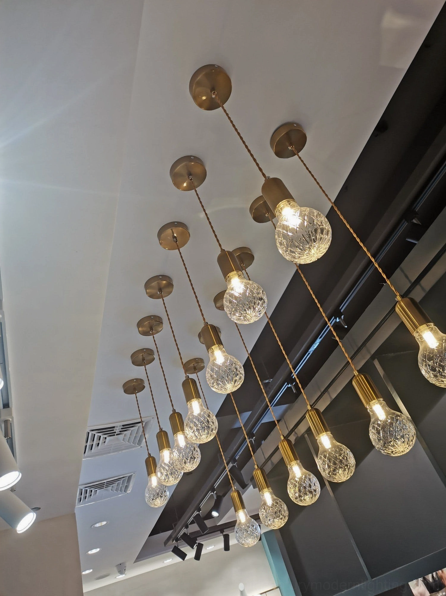 Large five-head crystal bulb chandelier in commercial high-ceiling space with gold branches