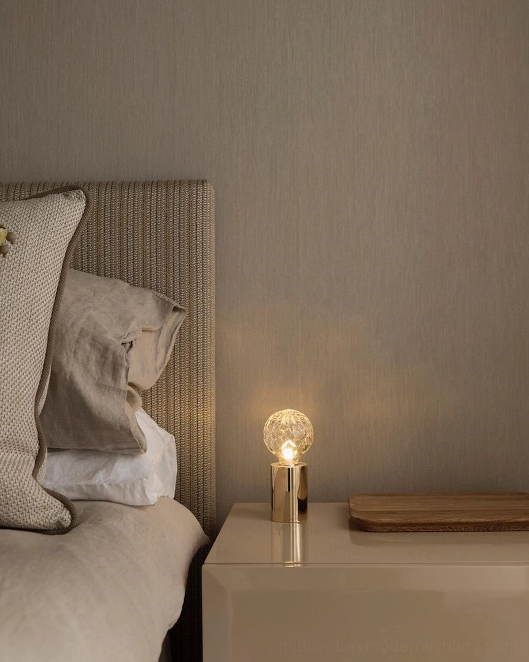 Compact crystal bulb bedside lamp with brass base providing warm ambient light on bedroom nightstand