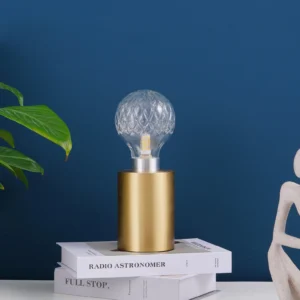 Modern crystal bulb desk lamp displayed on bedroom nightstand with blue wall and decorative books