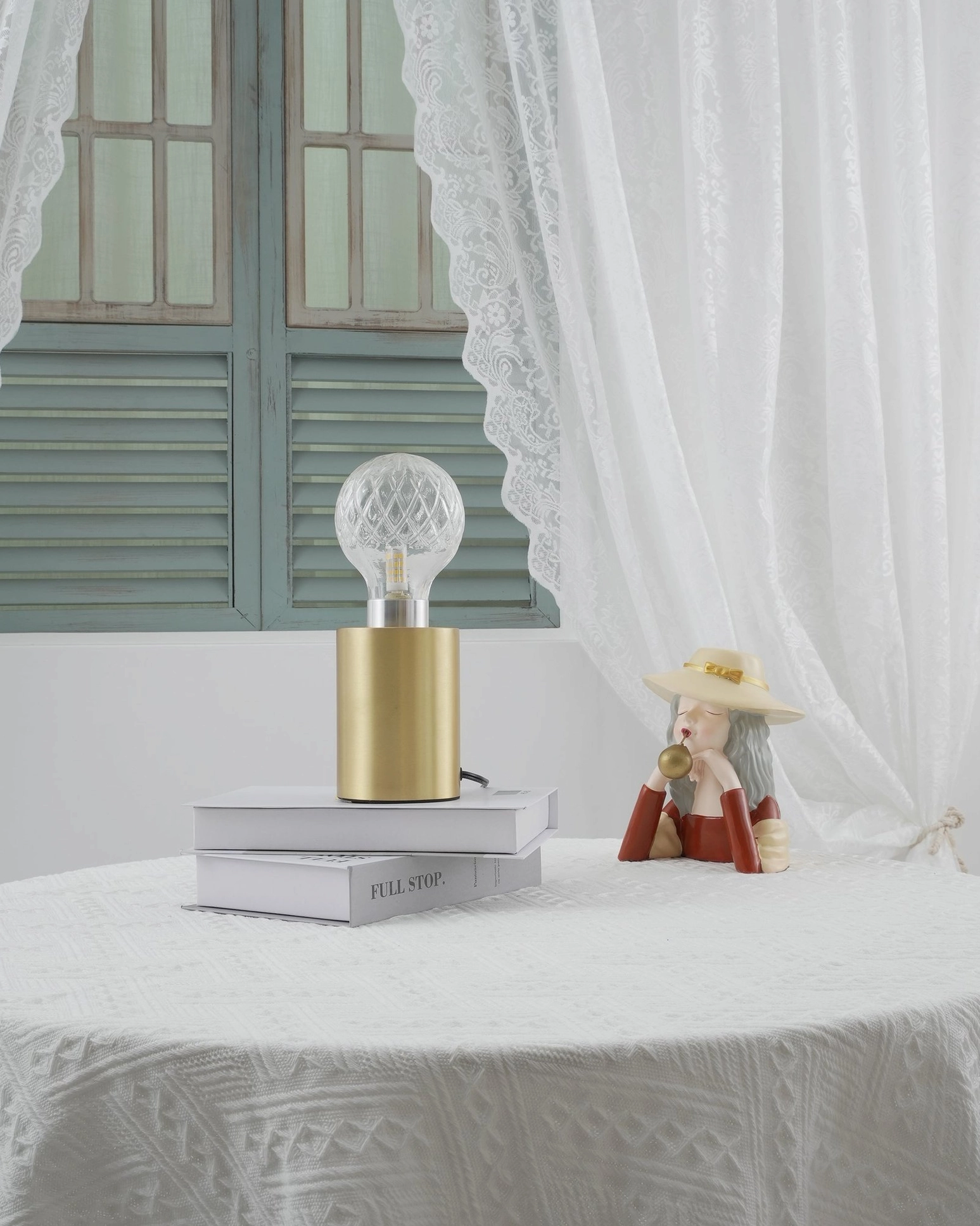Hand-cut crystal bulb table lamp styled with decorative doll and vintage accessories on round table