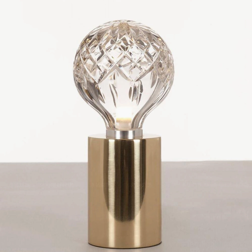 Minimalist crystal bulb table lamp with faceted glass shade on light colored desk surface
