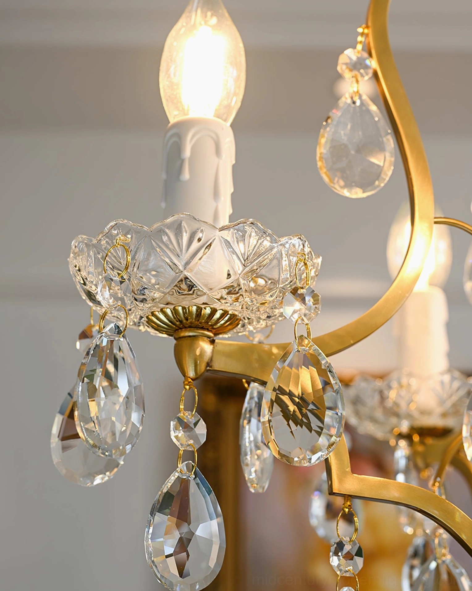 Detail view of cut-glass candle tray with curved gold arms and hanging crystal droplets