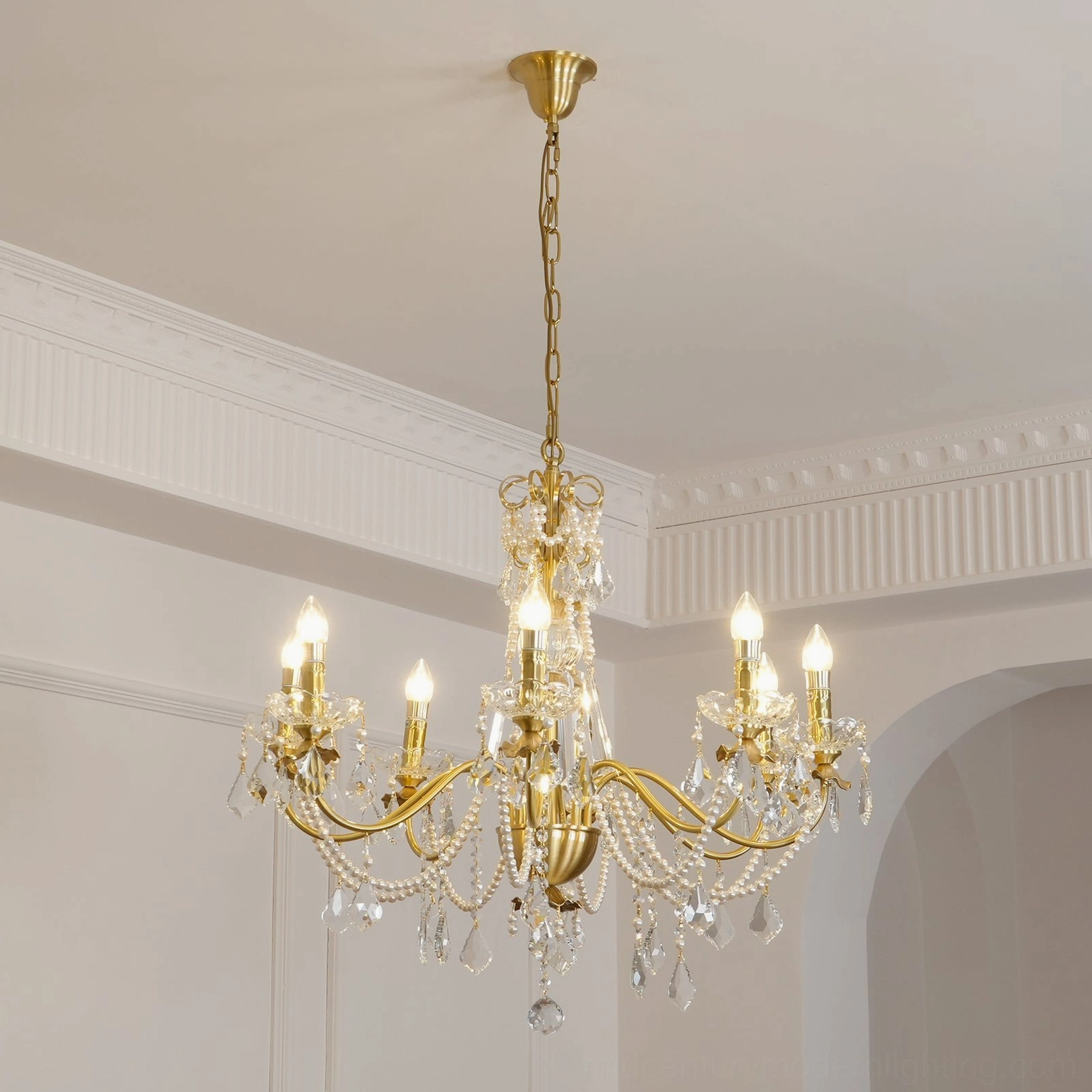 Elegant crystal chandelier with brass arms and pearl accents, close-up overhead view in classical interior