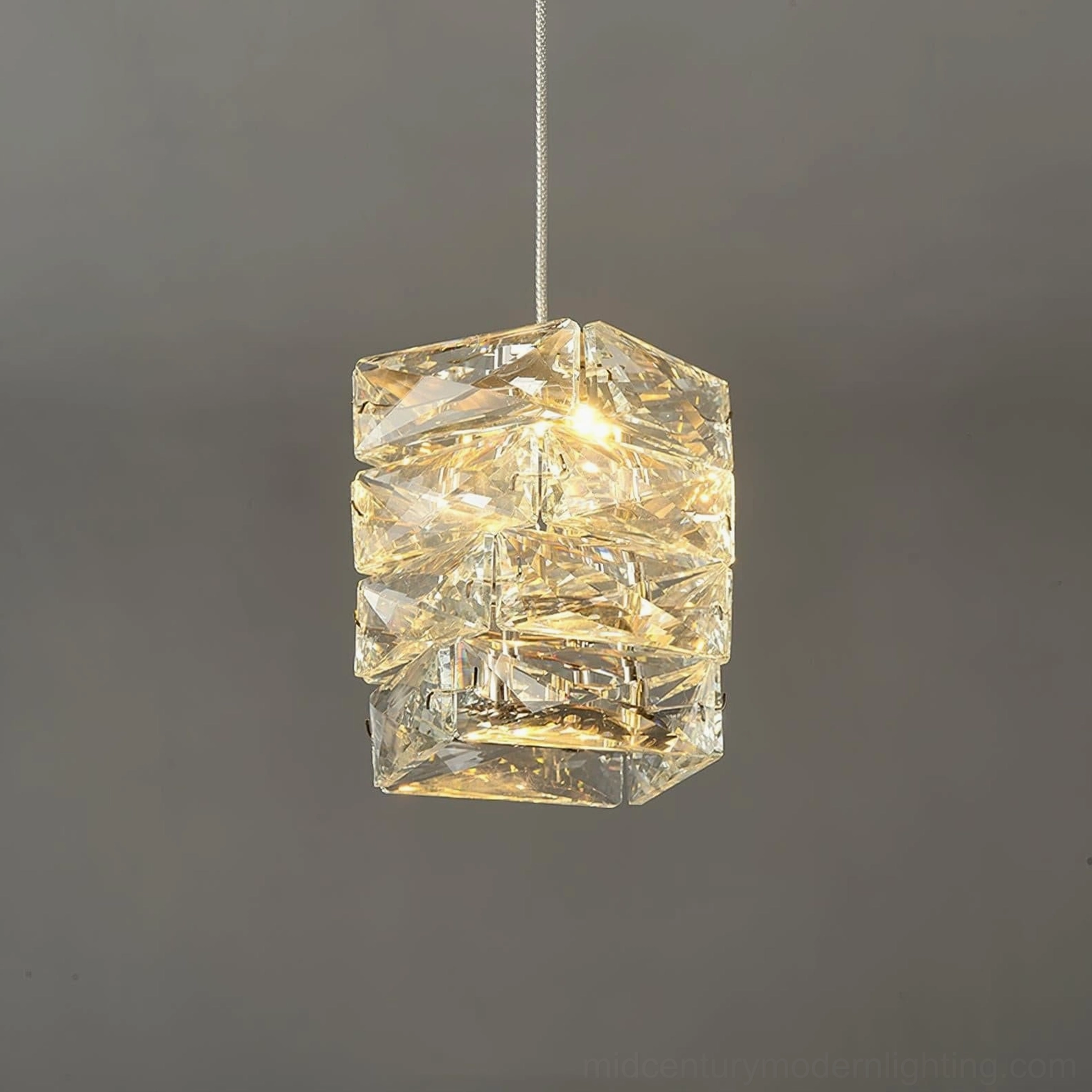 Faceted crystal cylinder pendant lamp suspended in modern minimalist interior with architectural design focus