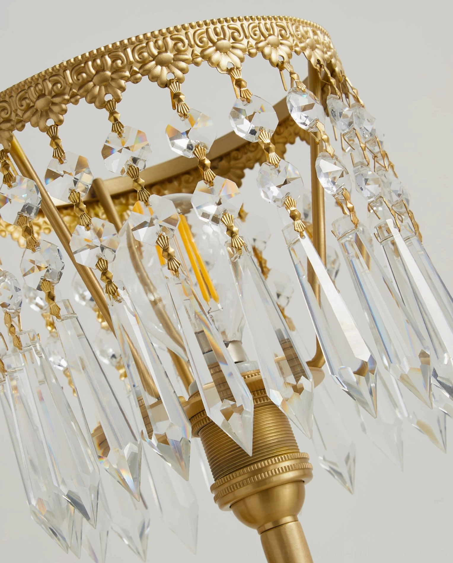 Crystal droplets pendant detail, carved brass frame holding hanging lead crystal teardrops catching light with prismatic effects