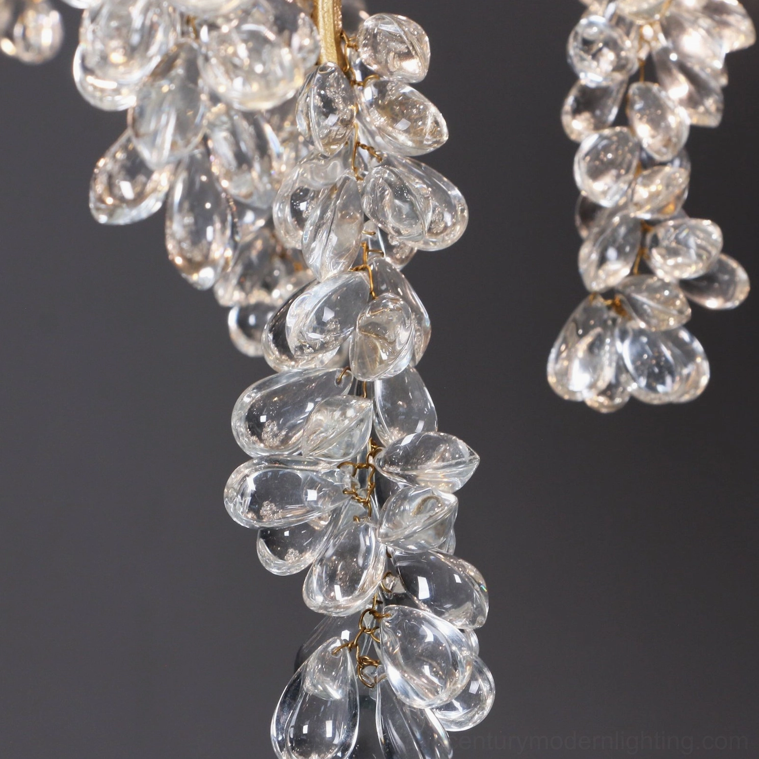 Flat macro photography of clear curved glass crystal grape pendants arranged in realistic cluster formation