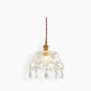 Crystal glass jewel pendant light with pressed floral pattern, gold brass fixture, studio front view