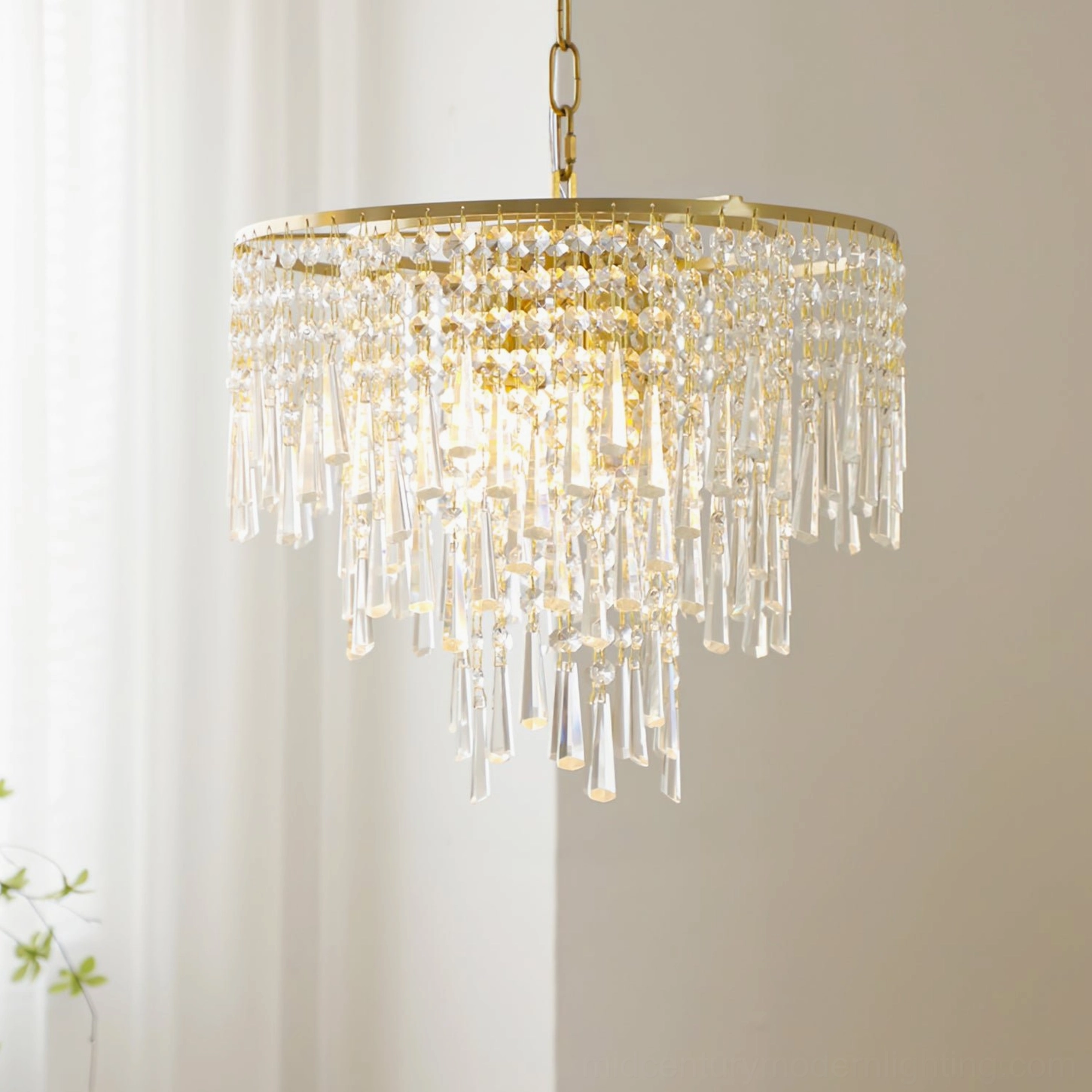 Close-up of crystal chandelier pendant glowing with warm interior light, featuring layered crystal tassel fringe and brass gold finish