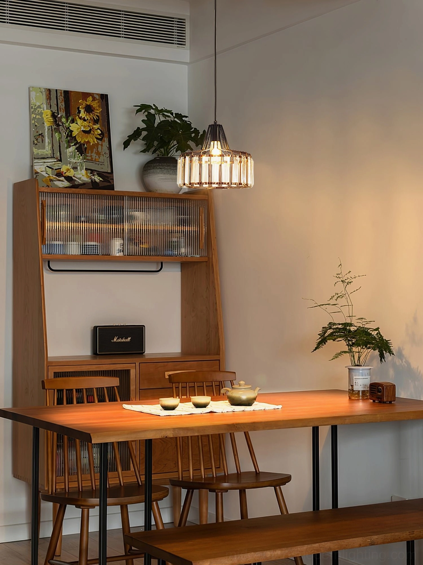 Crystal pendant ceiling lamp above wooden dining table in warm farmhouse modern dining room setting