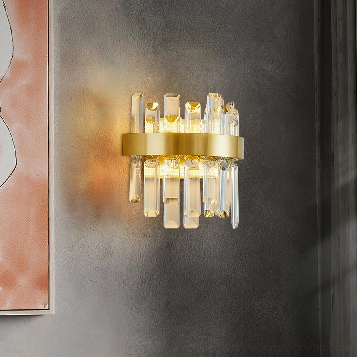 Close-up detail of brass crystal wall sconce with opaque crystal rods and gold-tone base against accent wall with abstract artwork