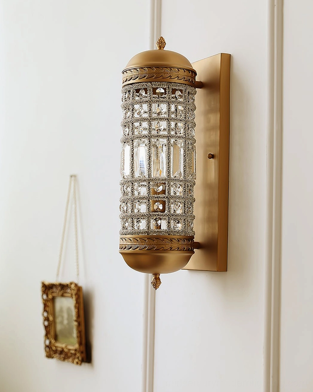 Wall lamp with hollowed crystal shade and brass hardware on white paneled wall