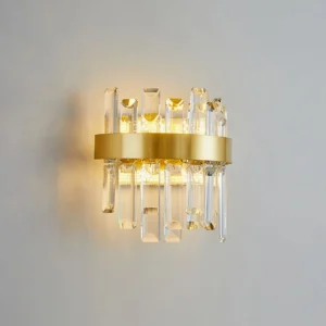 Crystal statement wall lamp mounted on light gray interior wall, illuminated with warm yellow light creating elegant shadow patterns