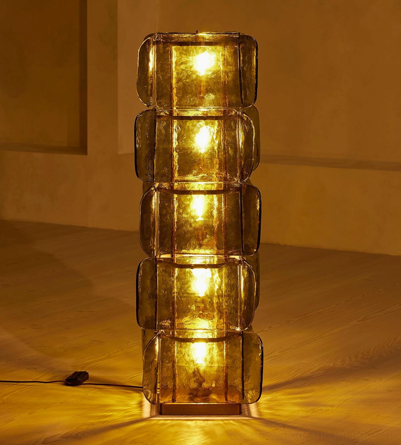 Illuminated olive green Cubo Totem floor lamp close-up, warm glowing glass tiers showcasing vintage luxury and moody ambiance