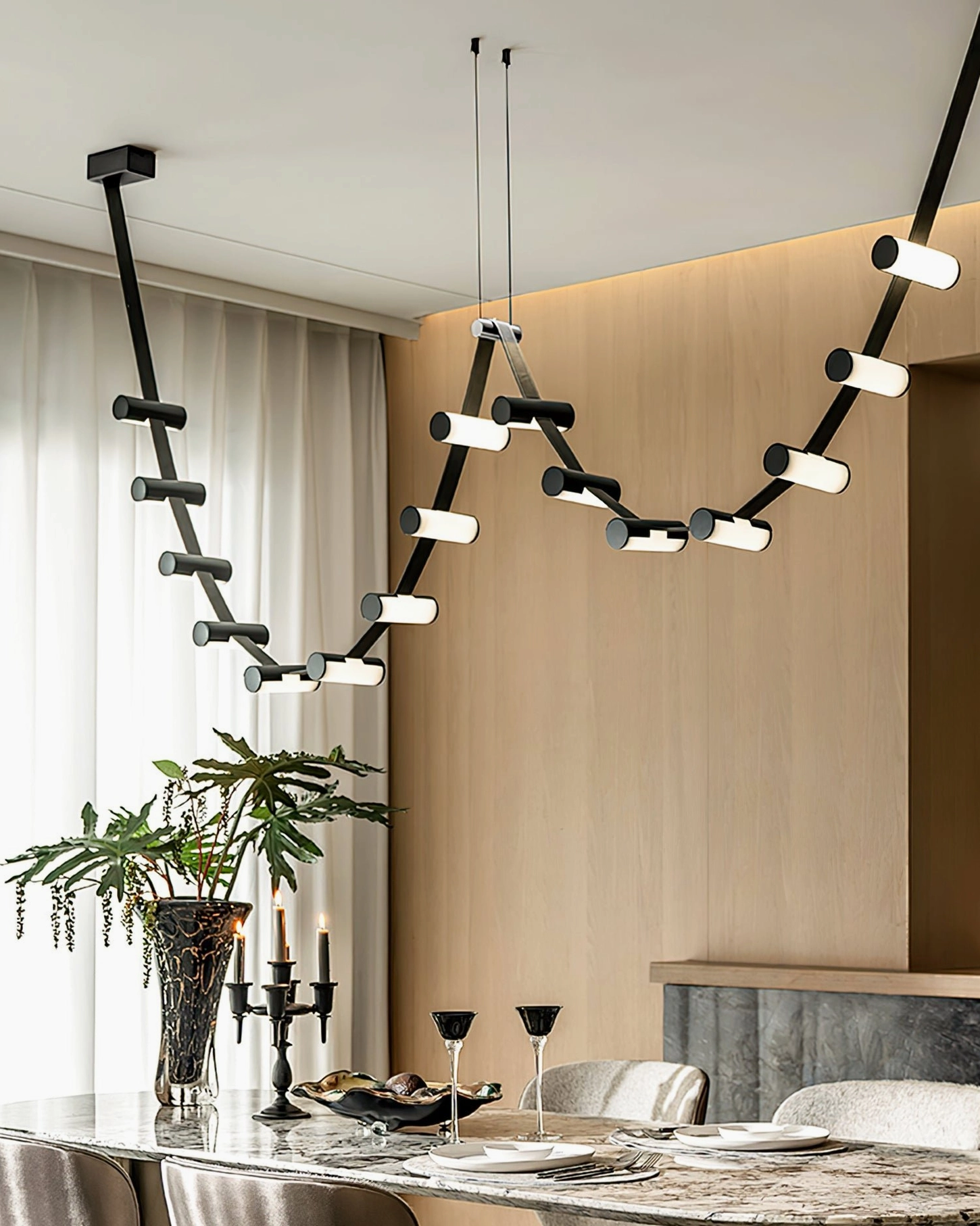 Adjustable wavy pendant chandelier in minimalist dining room, black metal frames with warm LED illumination