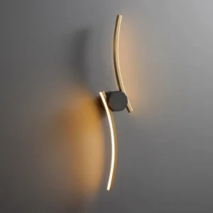 Modern curved wall sconce mounted on gray wall - warm brass finish with ambient glow