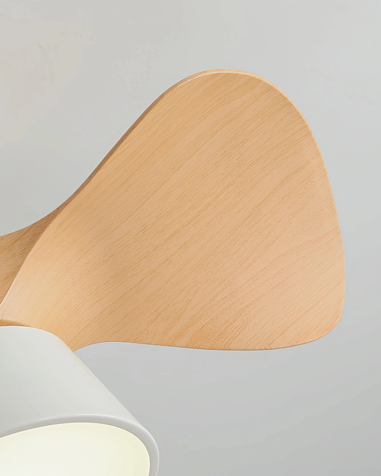 Side-view close-up of curved light wood grain fan blade from modern ceiling fan light fixture