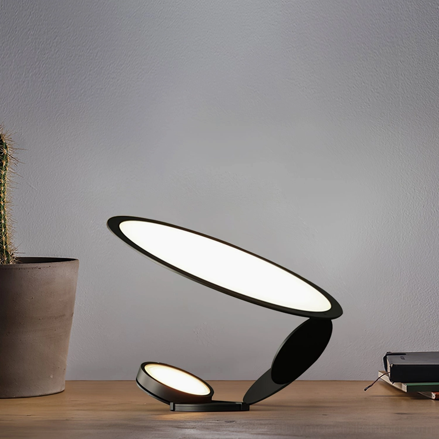 Minimalist laser-cut table lamp with dual oval light panels on wooden tabletop next to potted cactus plant