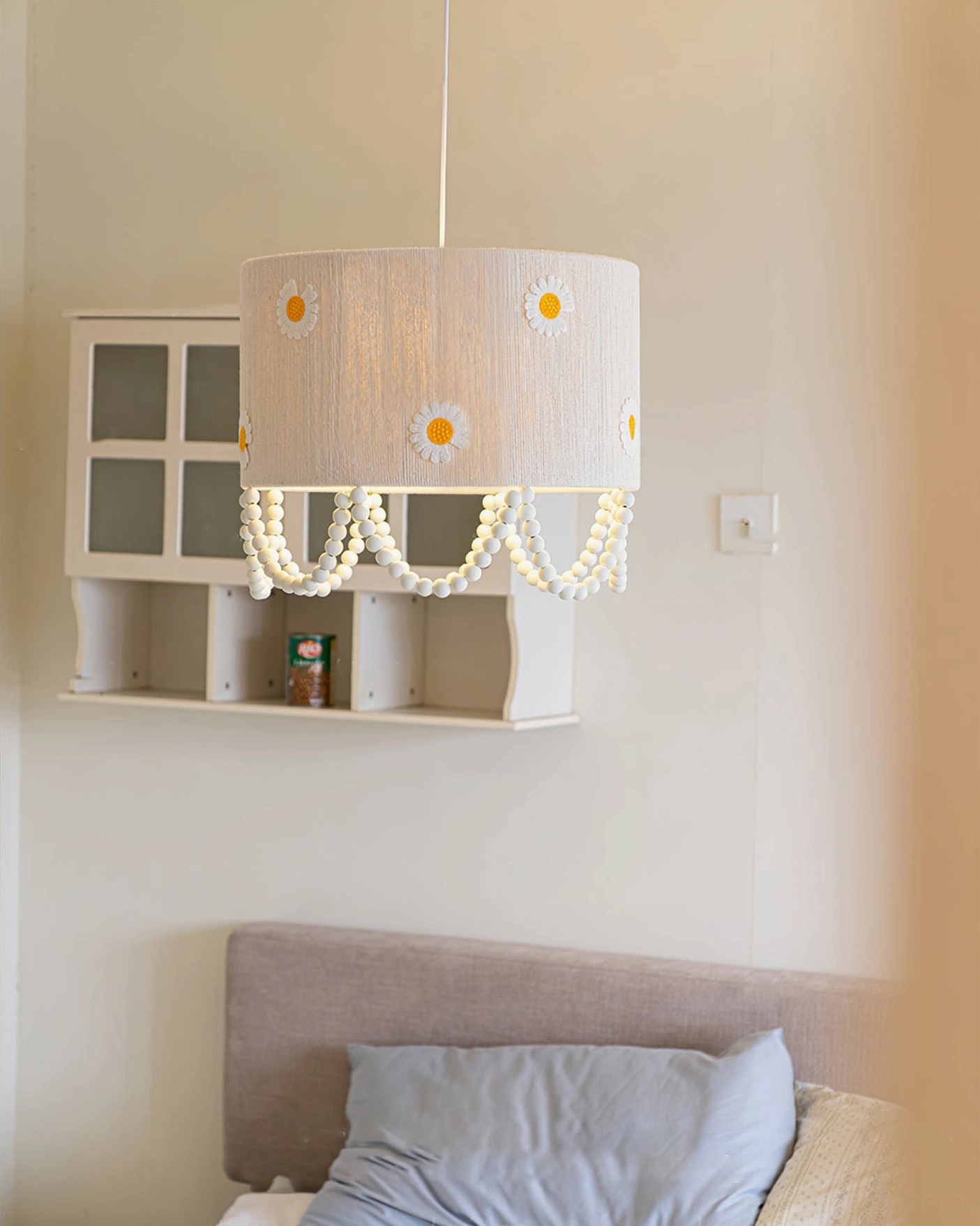 Daisy flower pendant lamp in cozy bedroom interior setting mounted above bed with wall shelf lifestyle photography