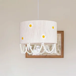 Close-up of daisy flower pendant lamp with woven texture yellow-center daisy motifs and draped pearl chain details indoor setting