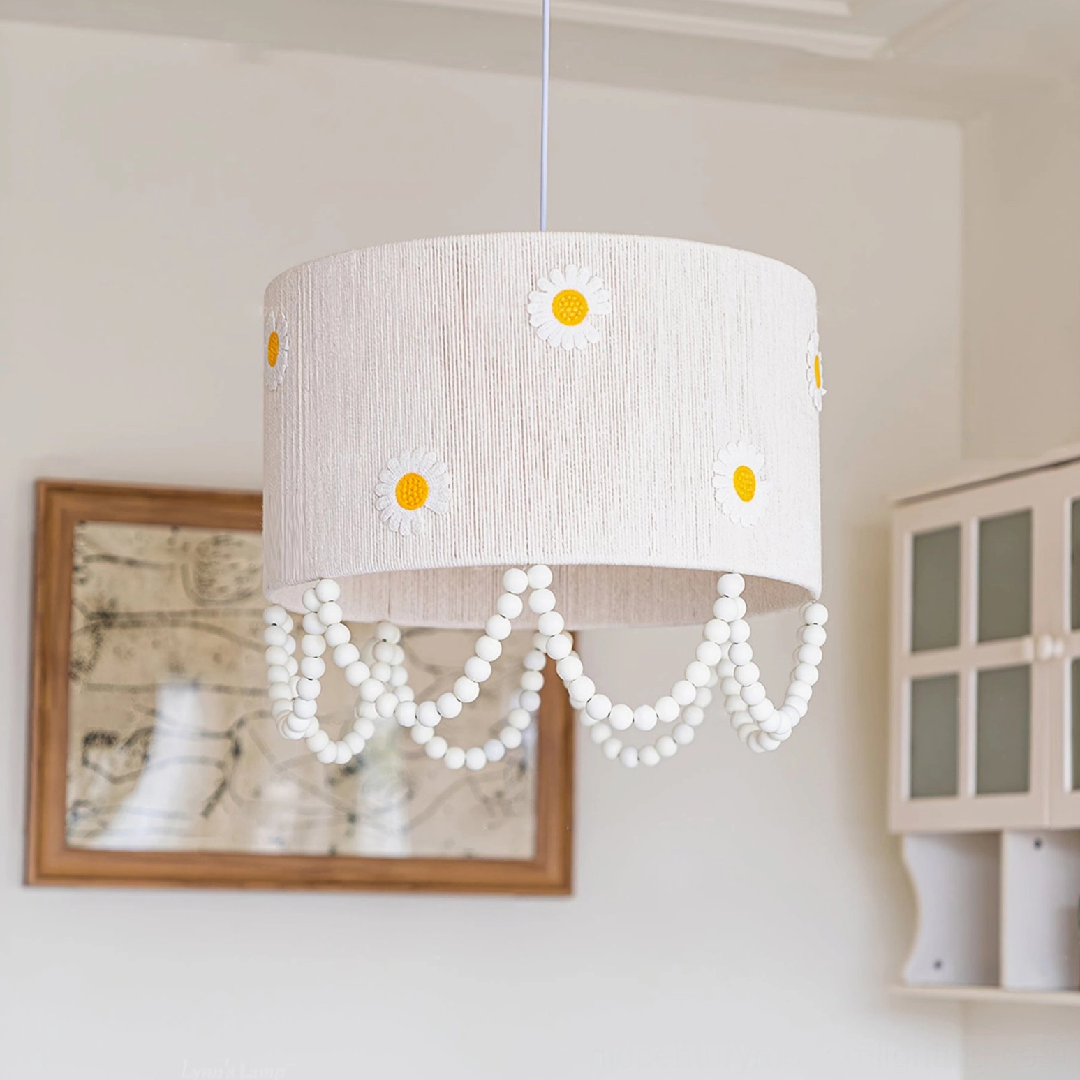 Daisy flower pendant lamp three-quarter view showing printed daisy shade and pearl bead draping in room interior
