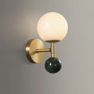 Close-up detail of Dalt globe wall lamp showing brass hardware, white frosted glass, and green marble base on grey background