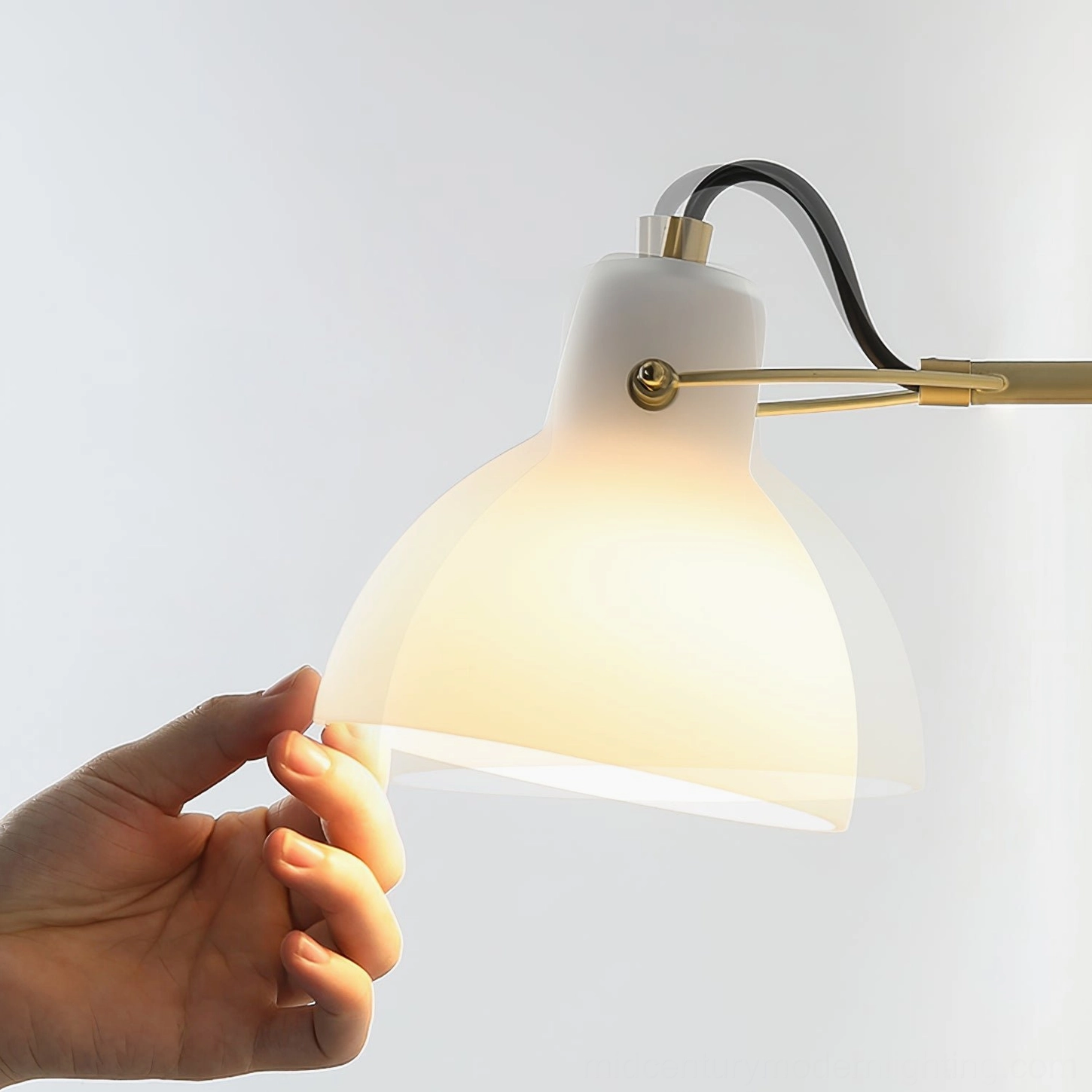 Hand adjusting Daniel swing arm wall lamp shade, demonstrating flexible positioning for warm ambient lighting