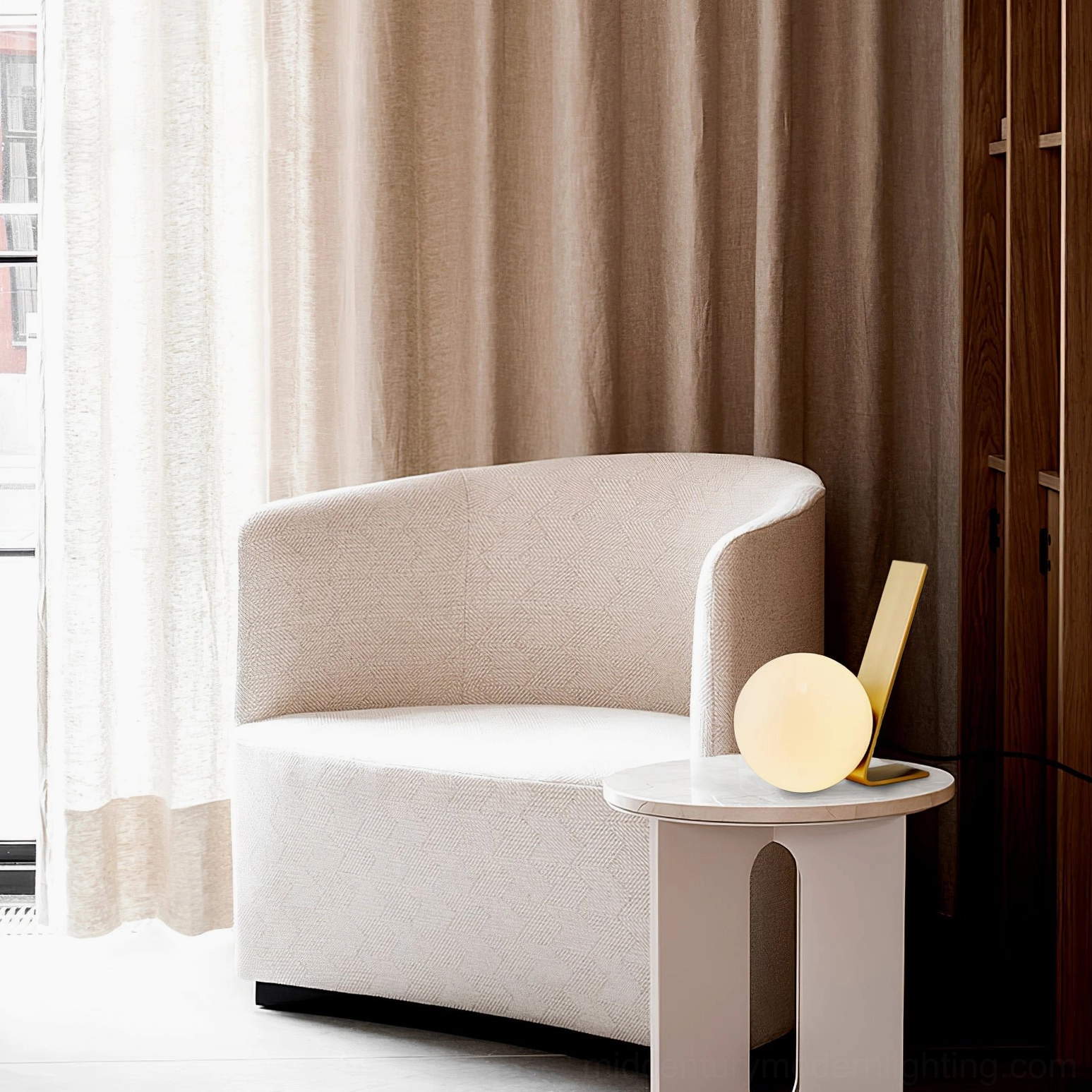 Daphne brass table lamp on white side table in bright casual seating area with armchair