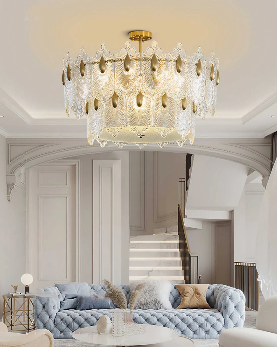 Foyer staircase Decazes chandelier, double-height entryway with blue tufted sofa, arched architecture, elegant home lighting