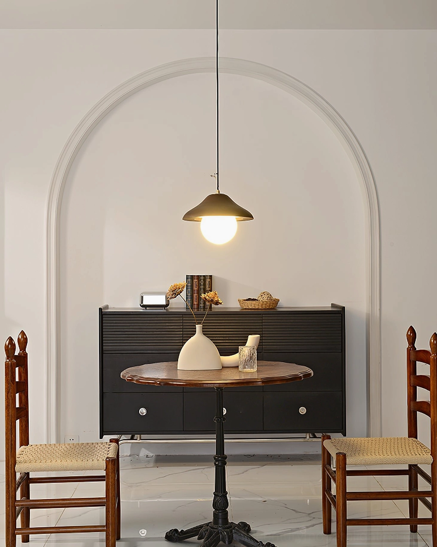 Delano compact pendant light in archway accent dining space, showcasing warm soft lighting and brass-finished hardware